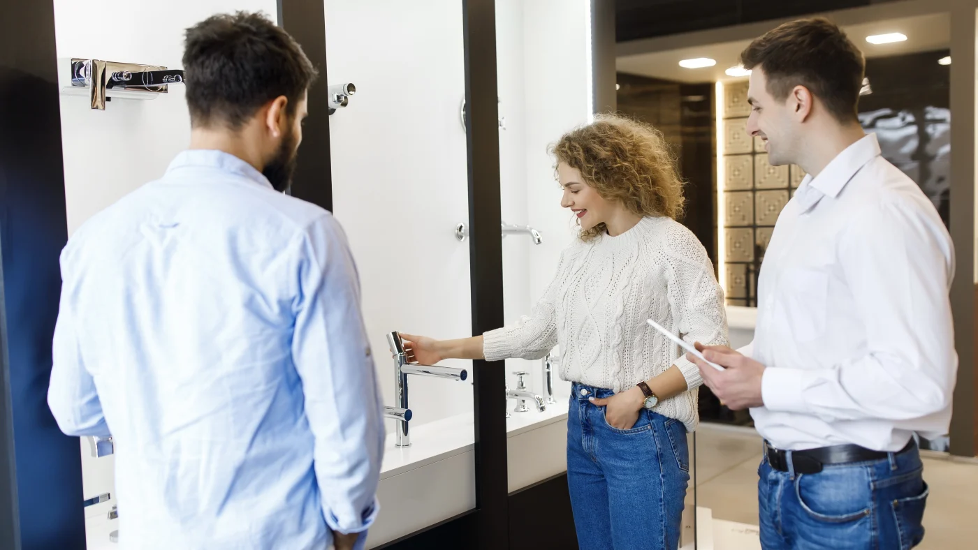 Two happy bathroom remodeling clients choose faucets with consultant