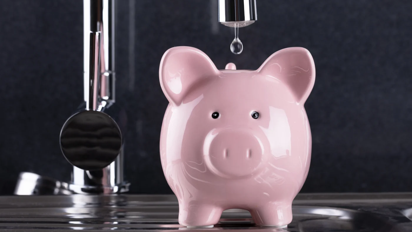 Piggy bank with water droplets dripping in from sink fixture