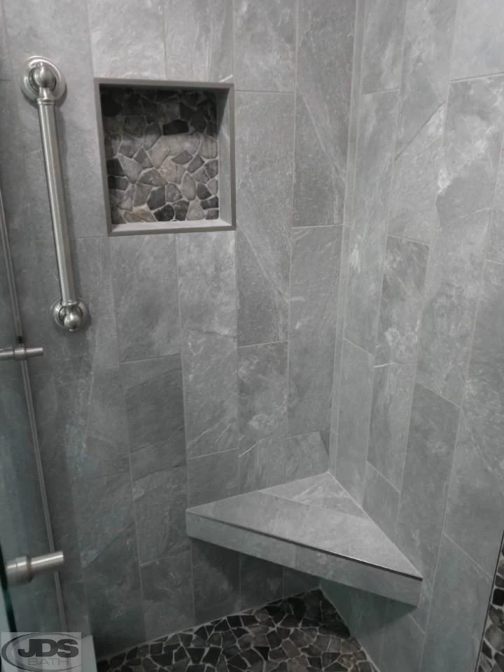 Closeup of built-in cubby and corner shelf, and vertical shower handle.