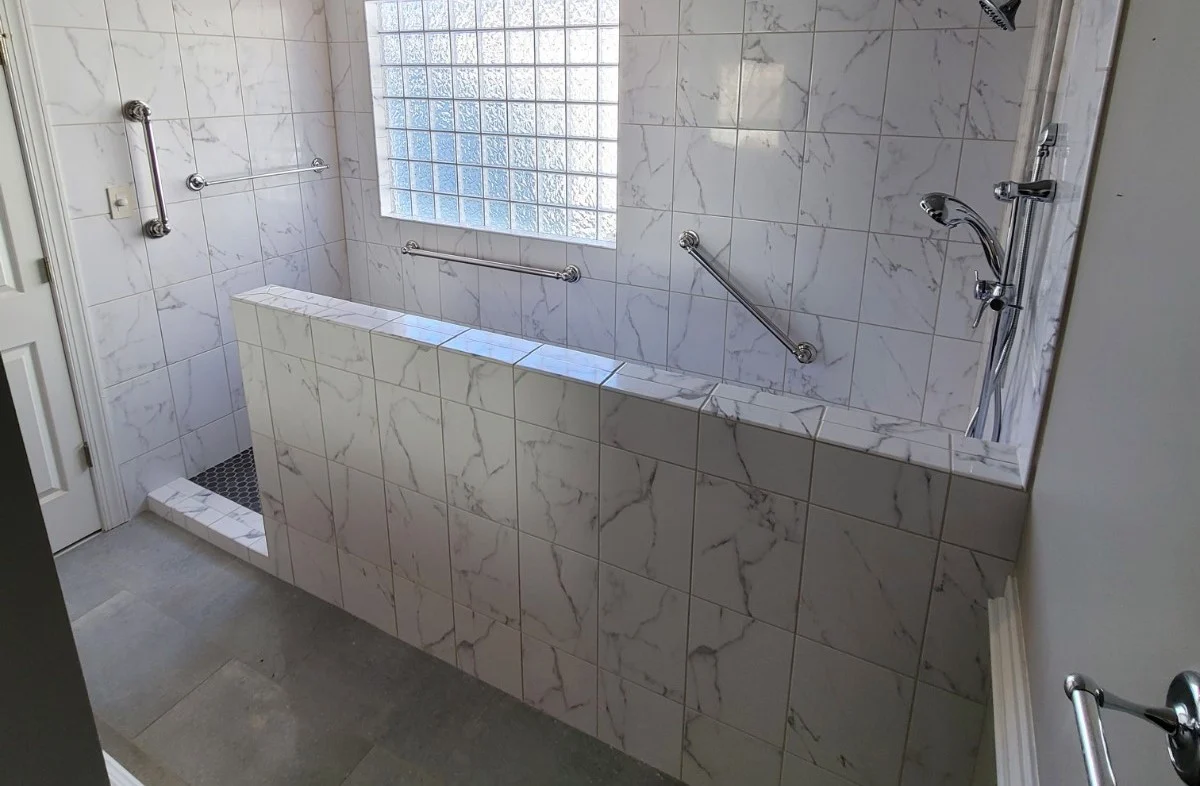 Long walk-in tile shower with grab bars