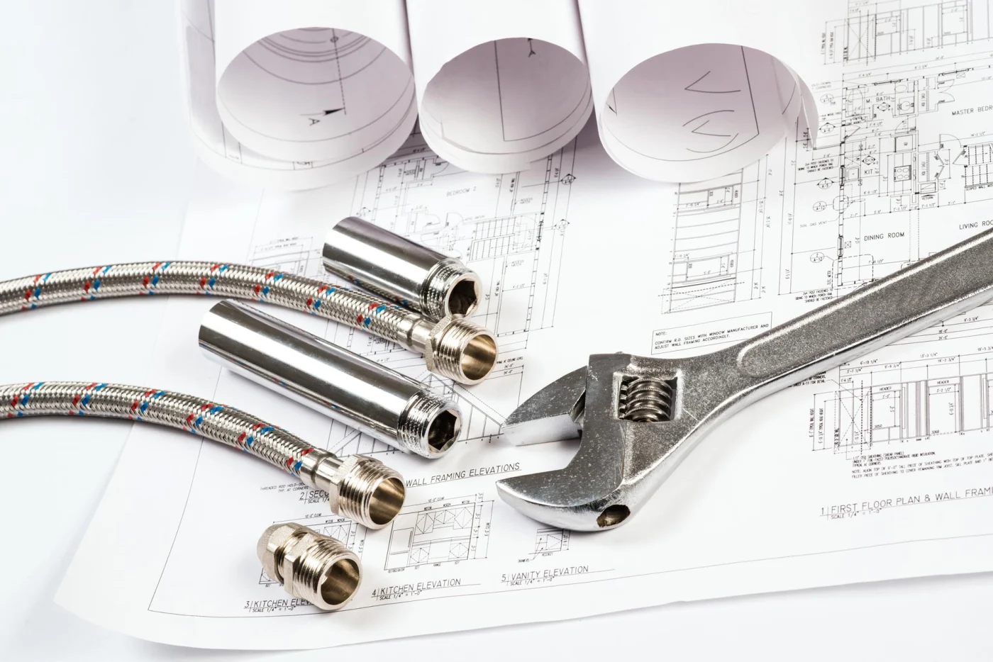 A wrench and wires lay on top of plans for a bathroom remodeling project.