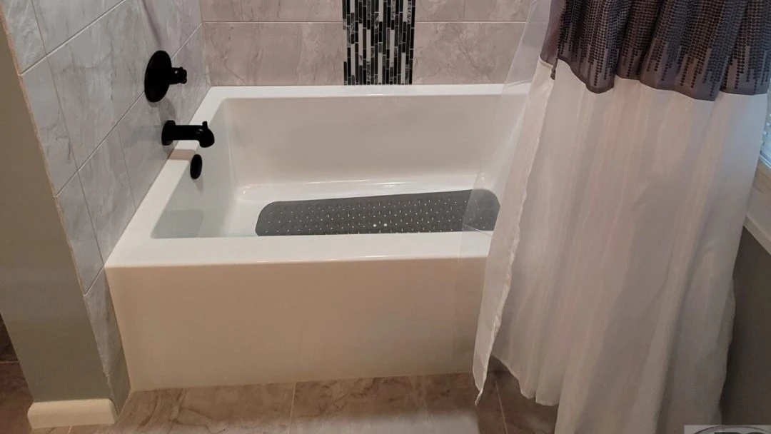 Close-up of newly installed modern bathtub with grey tile surround