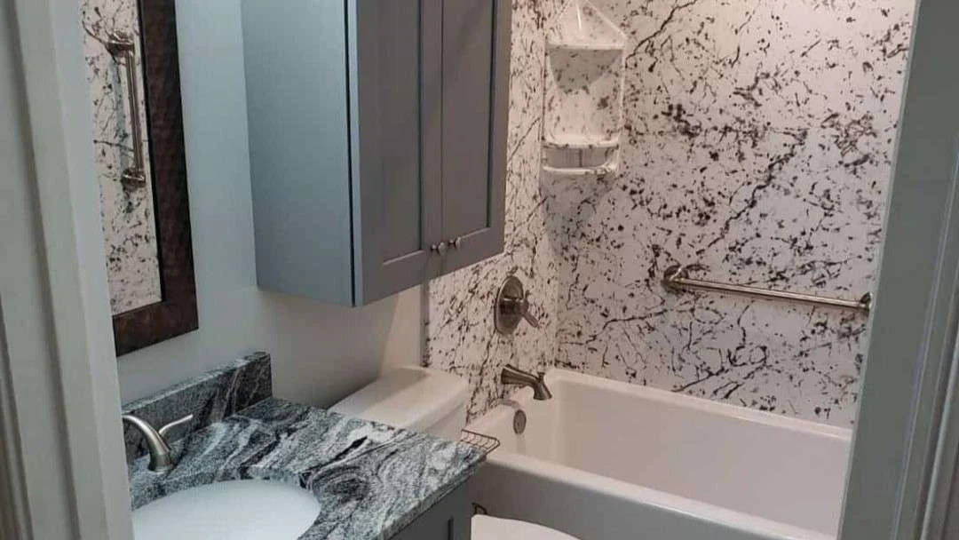 Newly remodeled bathroom with black and white shower remodel with pale green cabinetry