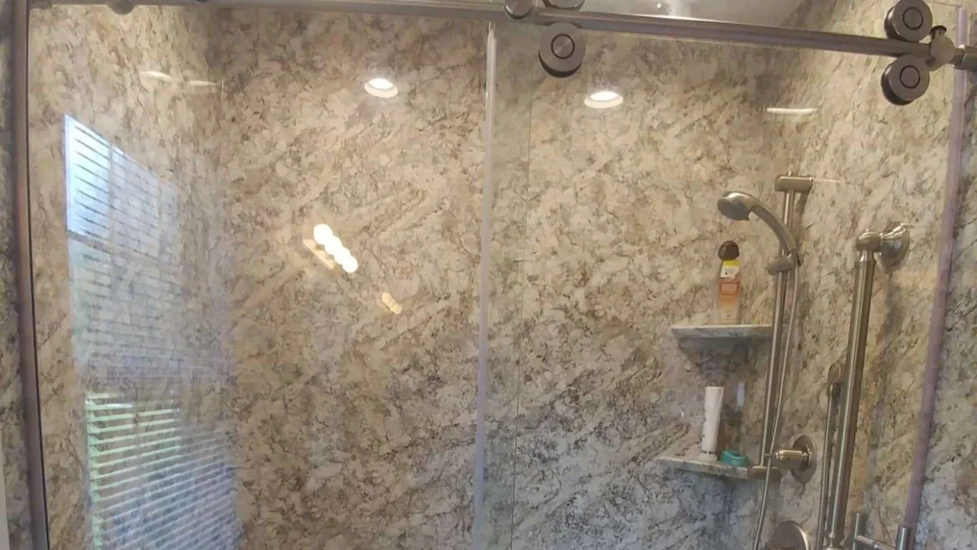 Large walk-in shower with sliding glass door and beautiful granite surround