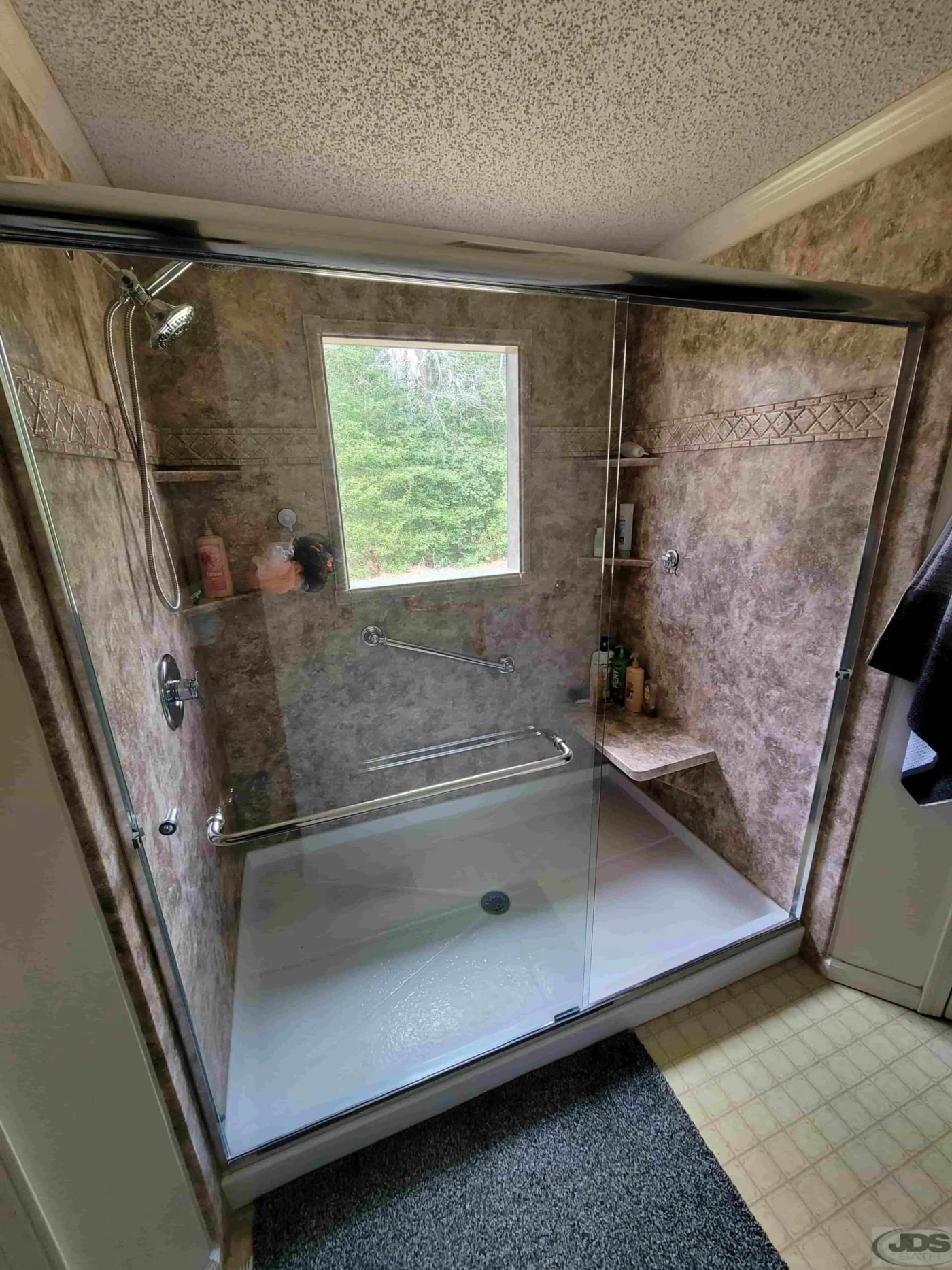 A spacious walk-in shower with a brown patterned acrylic shower surround.