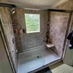 A new walk-in shower featuring a large window and built-in shelves.