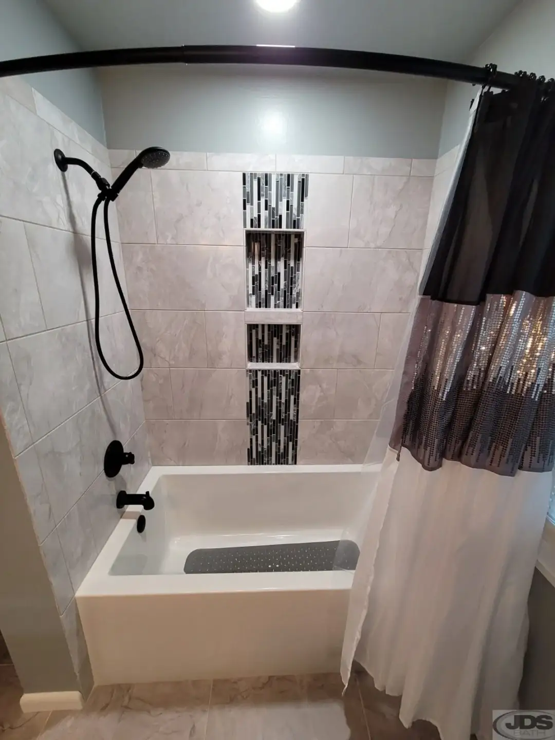 An acrylic bathtub with a beautiful tile surround was replaced in a bathroom.